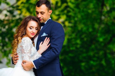 Yeni evliler gözlerini kapadılar ve ağaçların arka planına nazikçe sarıldılar.