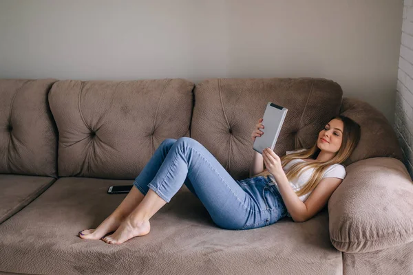 Feliz Hermosa Mujer Trabaja Tableta Encuentra Sofá Casa —  Fotos de Stock