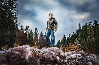 Hava bulutlu gökyüzüne bakarak askıya doğa yürüyen adam