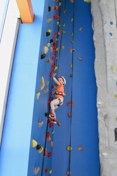 5 años de edad, niña en casco escalando una pared de roca interior — Foto de Stock