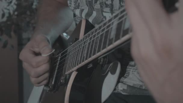 Een man speelt een zwarte elektrische gitaar — Stockvideo