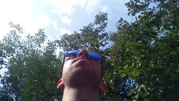 Jeune homme portant des lunettes de soleil bleues, vue du bas — Video