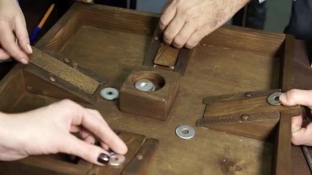 Un gioco da tavolo collettivo in cui le persone gettano trucioli di metallo . — Video Stock