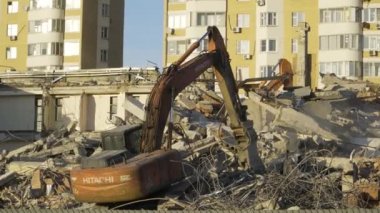 Bir demir dokunaç ile Ekskavatör takviye parçaları kapmak, imha edilmiş bir binanın kalıntıları üzerinde olmak. Şubat 2019, Moskova