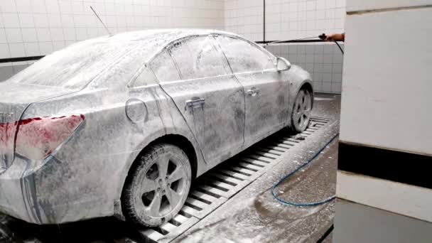 Coche en el lavado de coches todo cubierto con espuma . — Vídeo de stock