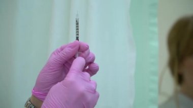 Doktor elinde bir şırınga tutar ve üzerinde parmaklarını tıklar