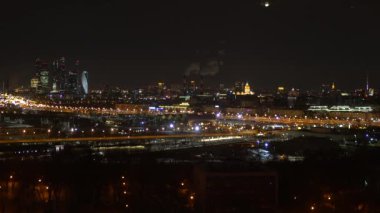 Gece metropolünün panoramik görünümü, görünür gökdelenler, Sigara borufabrikaları, geceleri şehrin ışıkları ve araba ların hareketi.