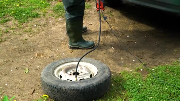 Ein Mann bläst ein altes Autorad mit einem Kompressor auf. — Stockvideo