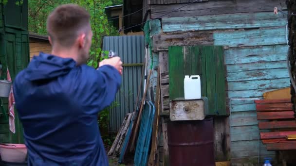 Um homem dispara uma arma contra uma lata cheia de água. . — Vídeo de Stock