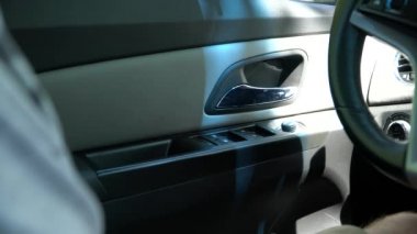 Arabada oturan bir adam kapı kolunu çeker.