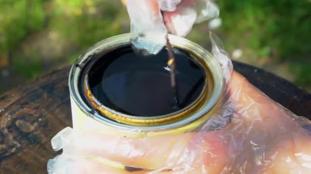 Человек перемешивает черную краску в жестяной банке — стоковое видео