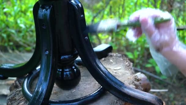 The man carefully paints the figured leg of the piano chair with a brush — Stock Video