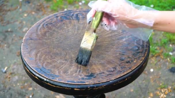 O homem gentilmente pinta escova com tinta preta ornamentada, velho banquinho de piano — Vídeo de Stock