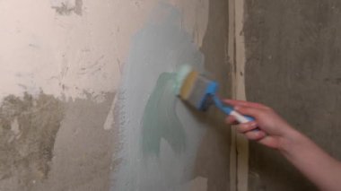 İki fırça ile eski gri-beyaz duvarda adam mavi ve zeytin boya neden olur