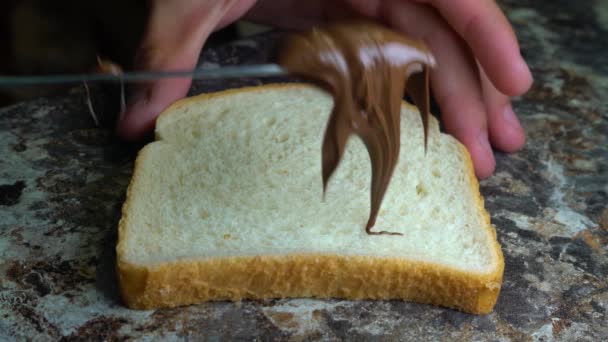 Çikolata ezmesi sandviçler için ekmek bir masa bıçağı ile yayıldı — Stok video