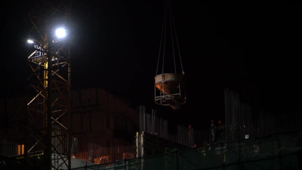 Sur le chantier de nuit, une grue soulève une bétonnière — Video