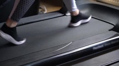 Fitness kulübündeki bir adam koşu bandında yürüyor.