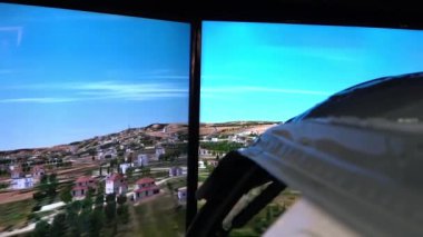 Helikopter simülatörünün kokpiti ekranın önünde yer alır