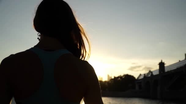 A menina dança lenta ao pôr-do-sol e ao rio — Vídeo de Stock