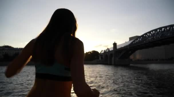 Meisje dansen tegen de zonsondergang en de rivier — Stockvideo