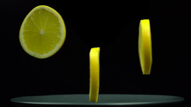 Drei Scheiben gelber Orange hängen in der Luft und rotieren auf schwarzem Hintergrund — Stockvideo