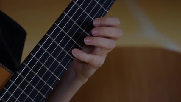 The fingers of a young man clamp the strings of a classical guitar — ストック動画