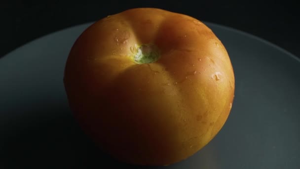 Die Tomate dreht sich auf dem Teller gegen den Uhrzeigersinn mit Beleuchtung auf der rechten Seite — Stockvideo