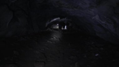 Bir grup insan mağaranın içinden fenerlerle geçer..