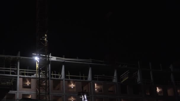 Por la noche en el sitio de construcción grúa torre baja la hormigonera — Vídeos de Stock