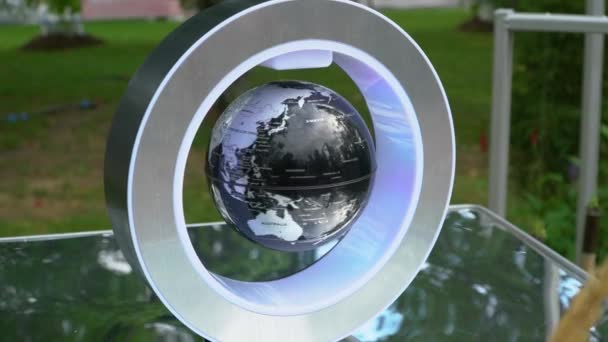 Маленька глобус висить у повітрі всередині кільця і обертається — стокове відео