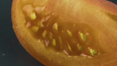 Bir dilim kırmızı domates yavaş bir mesafede gri bir plaka üzerinde döner.