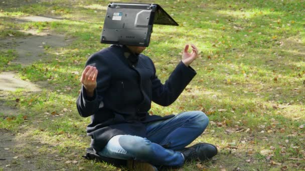 A business man sits in a coat in a Lotus position with a laptop on his head — Stock Video