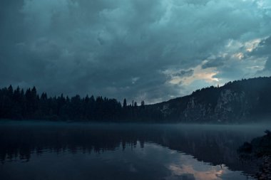 Nehirde gece sisi ve kayalık sahil.