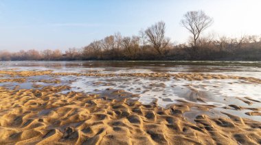 Soğuk bir kış sabahı, vahşi bir nehir kıyısında, kar ve donla