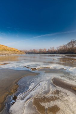 Soğuk bir kış sabahı, vahşi bir nehir kıyısında, kar ve donla