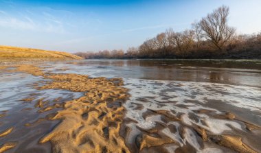 Soğuk bir kış sabahı, vahşi bir nehir kıyısında, kar ve donla