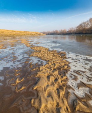 Soğuk bir kış sabahı, vahşi bir nehir kıyısında, kar ve donla