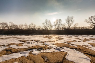 Soğuk bir kış sabahı, vahşi bir nehir kıyısında, kar ve donla