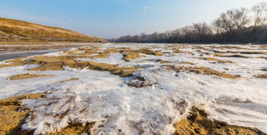 Soğuk bir kış sabahı, vahşi bir nehir kıyısında, kar ve donla