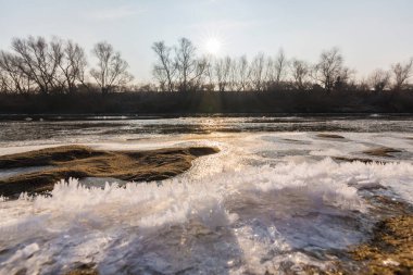 Soğuk bir kış sabahı, vahşi bir nehir kıyısında, kar ve donla