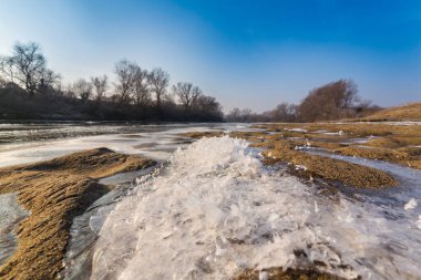Soğuk bir kış sabahı, vahşi bir nehir kıyısında, kar ve donla