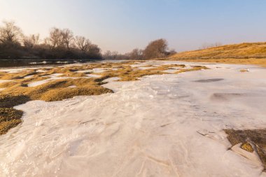 Soğuk bir kış sabahı, vahşi bir nehir kıyısında, kar ve donla