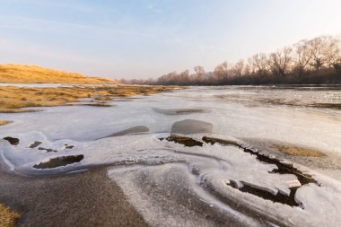 Soğuk bir kış sabahı, vahşi bir nehir kıyısında, kar ve donla