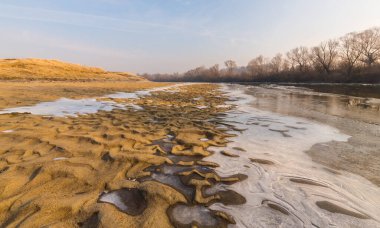 Soğuk bir kış sabahı, vahşi bir nehir kıyısında, kar ve donla