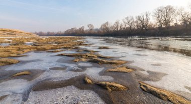 Soğuk bir kış sabahı, vahşi bir nehir kıyısında, kar ve donla