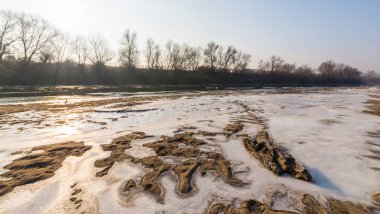 Soğuk bir kış sabahı, vahşi bir nehir kıyısında, kar ve donla