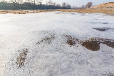 Soğuk bir kış sabahı, vahşi bir nehir kıyısında, kar ve donla