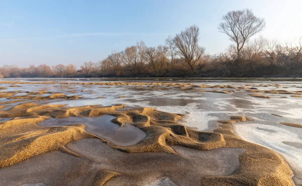 Soğuk bir kış sabahı, vahşi bir nehir kıyısında, kar ve donla