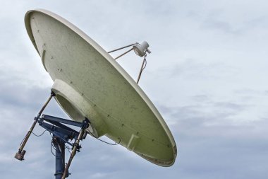 Bulutlu gökyüzü arka planında yüksek teknoloji ve modern uydu çanağı