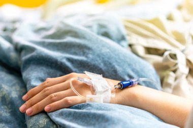 Hastane koğuşundaki bir hastanın eline odaklan. Damardan salin verilmesi sırasında yatağın üzerine.